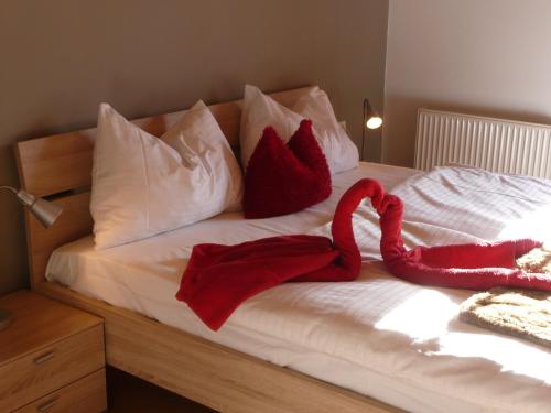 a bed with two red velvet pillows on it at Haus Rosi in Uttendorf