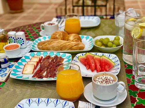 a table with plates of food and cups of orange juice at La Esperanza Granada Luxury Hacienda & Private Villa in Saleres