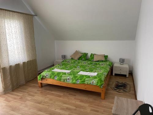a bedroom with a bed with a green comforter at Vila Ekooos in Braşov