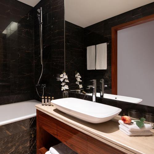 a bathroom with a sink and a bath tub at The Bentley Luxury Hotel & Suites in Doha