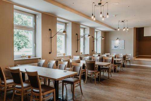 a dining room with tables and chairs and windows at HÖNOW HOTEL in Hoppegarten