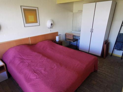 a bedroom with a pink bed and a cabinet at Holiday Home Marielyst IV in Marielyst