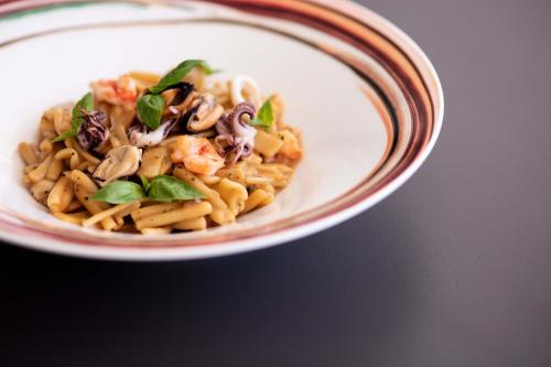 a bowl of pasta with seafood and basil on a table at Laqua by the lake in Pettenasco