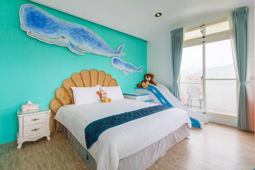 a bedroom with a blue wall with a bed with dolphins on it at Footprint Garden B&B in Dongshan