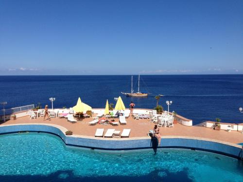 a person standing in a swimming pool next to the ocean at Hotel Carasco in Lipari