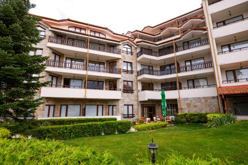 an apartment building with a lawn in front of it at Parklands Hotel & Pool in Bansko