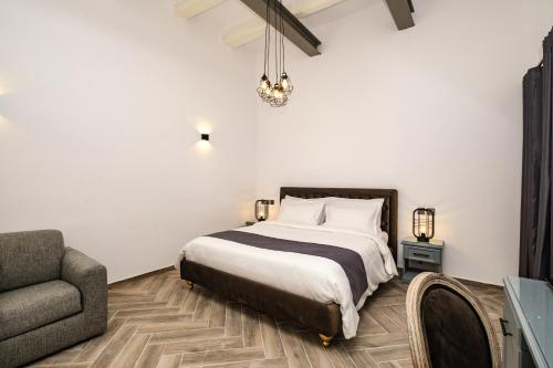 a bedroom with a bed and a chair and a couch at Casa Reale Boutique Hotel in Valletta