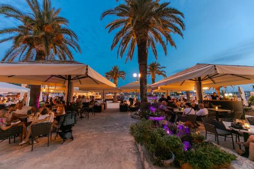 a group of people sitting at tables under umbrellas at Hotel Concordia in Trogir
