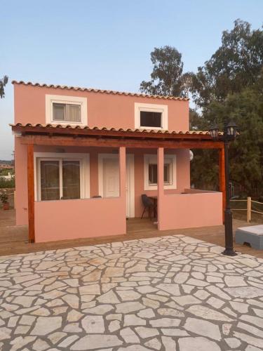 a small pink house with a stone patio at Perland Vacation in Sidari