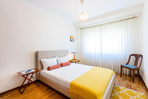 a small bedroom with a bed and a chair at Espinho Sunshine Flat in Espinho