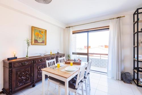a dining room with a table and a large window at Espinho Sunshine Flat in Espinho