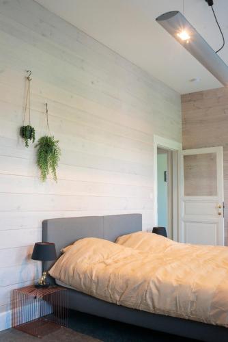 a bedroom with a bed and a white wall at Avant Garde in Watou