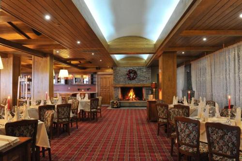 a restaurant with tables and chairs and a fireplace at Pirin Golf Hotel Private Apartments Апартаменти Планински Изгрев в Пирин Голф in Razlog
