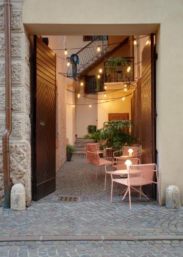 a patio with chairs and tables in a building at Goldengel Design - Suiten im historischen Ortskern von Kaltern in Caldaro