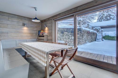 Un comedor con mesa y sillas y una gran ventana. en Les Gravillons, en Morzine