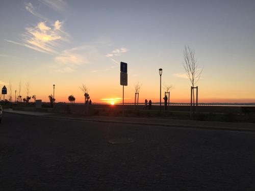 a sunset on a street with the sun setting at Coração da Vila in Alcochete