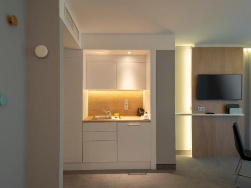 a kitchen with white cabinets and a sink and a tv at Holiday Inn Express - Offenbach by IHG in Offenbach
