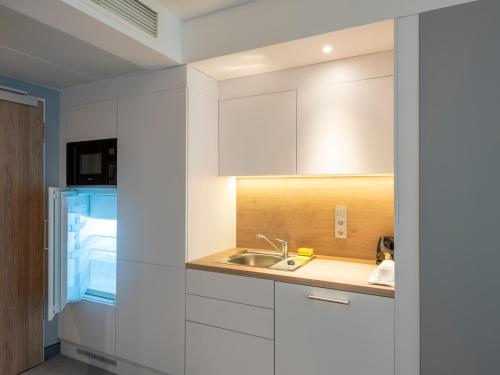 a kitchen with white cabinets and a sink at Holiday Inn Express - Offenbach, an IHG Hotel in Offenbach