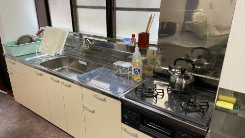 a kitchen with a sink and a stove top oven at ゲストハウス　華屋 (guest house HANAYA） in Sado