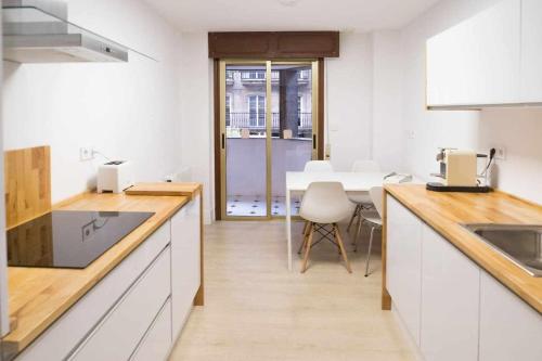 a kitchen with white cabinets and a dining table at RyS Ourense Centro PARKING Gratis in Ourense