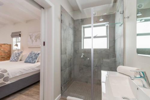 een badkamer met een douche, een bed en een wastafel bij Ebb in Knysna