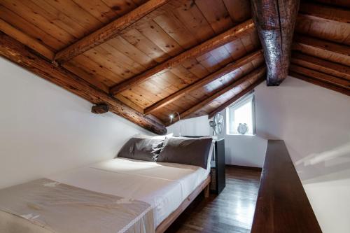 1 dormitorio con cama y techo de madera en Suite Fontana - by MyHomeInComo, en Como