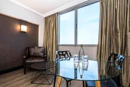 a dining room with a glass table and chairs at Belaire Suites Hotel in Durban