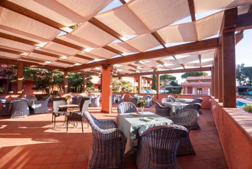 a patio with tables and chairs under a wooden pergola at Hotel Residence Villa San Giovanni in Portoferraio