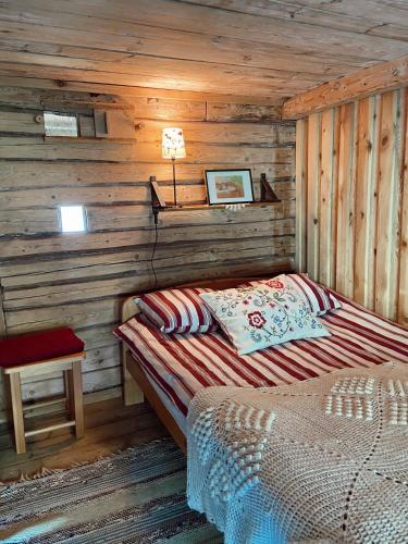 a bedroom with a bed in a wooden cabin at Muhu Tõnise Talu in Liiva