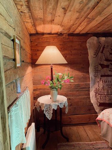 a room with a table with a lamp and flowers on it at Muhu Tõnise Talu in Liiva