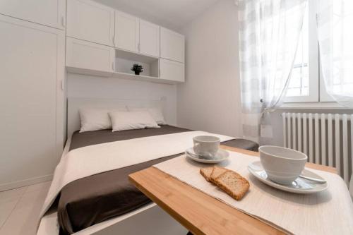 ein Schlafzimmer mit einem Bett und einem Tisch mit zwei Scheiben Brot in der Unterkunft NUOVO LOFT al MARE con PARCHEGGIO GRATUITO in Misano Adriatico