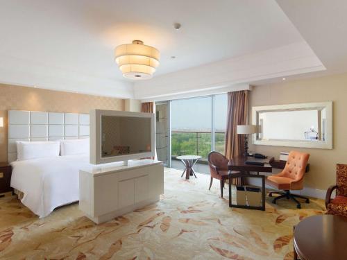 a bedroom with a bed and a desk with a television at Fairmont Yangcheng Lake in Kunshan