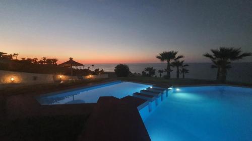 a swimming pool with a sunset in the background at Stella Beach Hotel in Panormos Rethymno