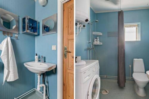 y baño azul con lavabo y lavadora. en Trevlig stuga med endast 300 m till Dalälven., en Rudö