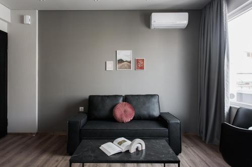 アテネにあるWYZ Athens Apartments by UPSTREETのリビングルーム(黒いソファ、テーブルの上に靴付)