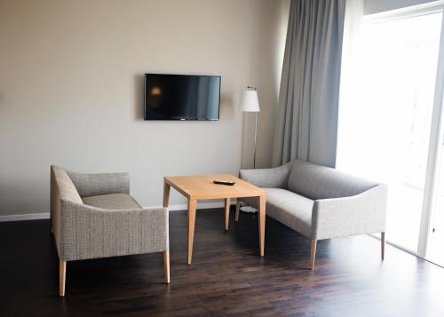 a living room with two chairs and a table and a tv at Hotel Öresund Conference & Spa in Landskrona