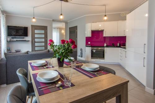 a kitchen and living room with a wooden table with roses at Apartamenty Izerskie - ul. Cicha 13F-G in Świeradów-Zdrój