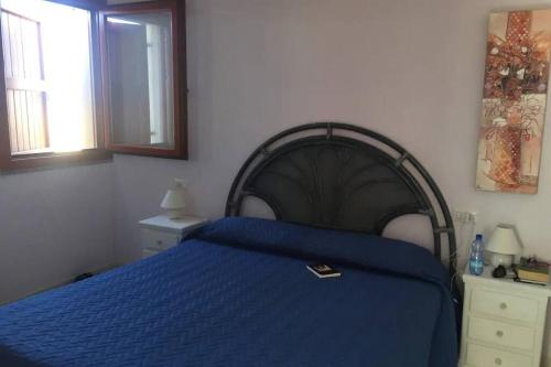 a bedroom with a blue bed and two windows at Mare, dune, lago e bosco in assoluto relax. in Torre Dei Corsari