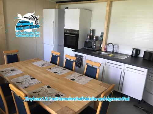 a kitchen with a wooden table with chairs and a refrigerator at Unterkünfte bei Wake and Beach am Halbendorfer See in Schleife