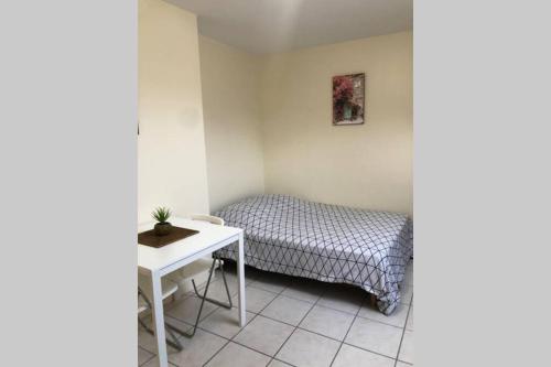 une petite chambre avec un lit et une table dans l'établissement Studio Cosy 2 PERS, à Longjumeau
