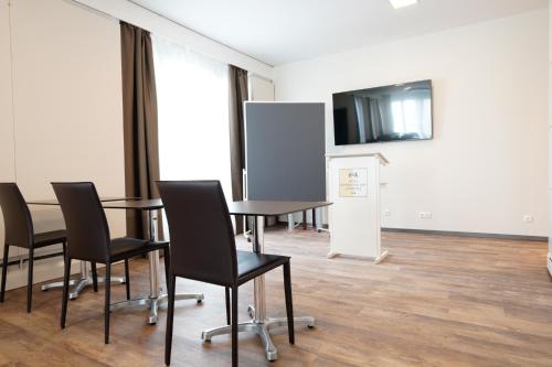 a conference room with a table and chairs and a screen at Hotel Bayerischer Hof in Bayreuth