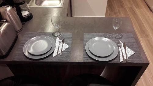 a table with two plates and two wine glasses at Acropolis-view brand new modern apartment at Ermou in Athens