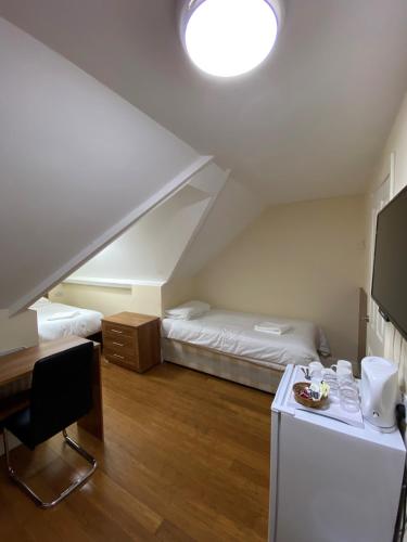 a room with two beds and a desk in a attic at Buckingham Hotel in High Wycombe