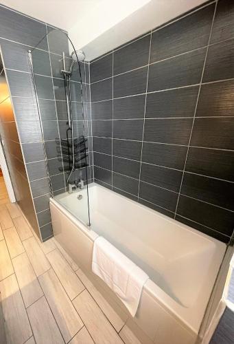 a bathroom with a white tub and gray tiles at Chalet Pitu - 1-6 People in Vénosc
