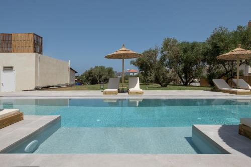 a swimming pool with chairs and umbrellas at Casa Nostos in Agia Marina Nea Kydonias