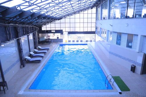 a large swimming pool with blue water in a building at ELGEL Hotel and Spa in Nefas Silk