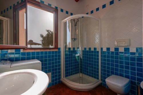 uma casa de banho em azulejos azuis com um chuveiro e um lavatório. em Cedri 14 em Capitana