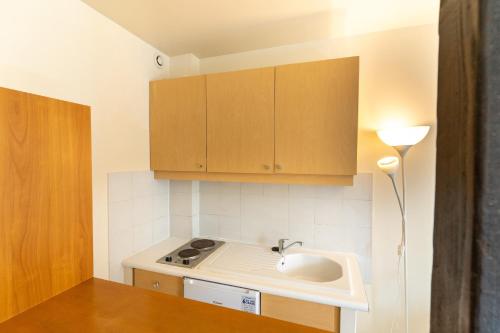 a small kitchen with a sink and wooden cabinets at Hôtel Capfun Le Saint Germain, Paris in Paris