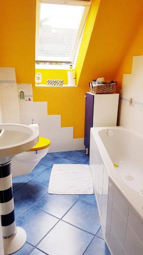 a yellow bathroom with a sink and a tub and a sinkessment at Ferienwohnung Kochel mit Wallbox in Gifhorn