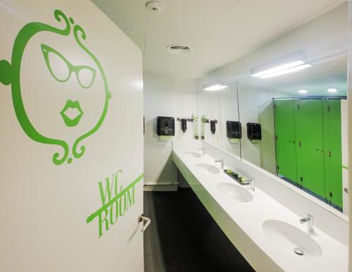 a bathroom with two sinks and a green sign on the wall at Room018BCN in Barcelona